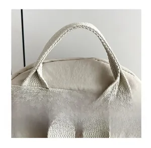Detail of the reinforced top handle and shoulder straps on a beige nylon backpack