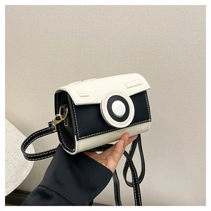 Detailed view of a retro camera-shaped crossbody bag with black and white contrast stitching