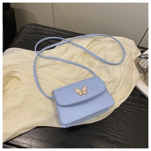 Close-up of a light blue faux leather crossbody bag with a golden butterfly clasp detail