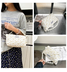 Détail du sac à main matelassé blanc avec broderie papillon jaune et poignée perle