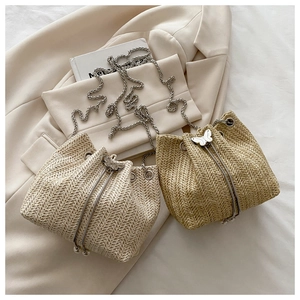 Detail of straw bucket bags showing drawstring closure with butterfly metal buckle
