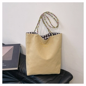 Détail du sac fourre-tout en toile kaki avec broderie dorée et bandoulière en perles colorées