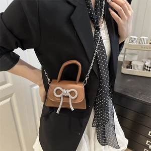 Mini sac bandoulière marron avec nœud en cristal et chaîne argentée porté par mannequin