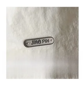 Close-up of the metal logo plaque and wrinkled texture on a white nylon backpack