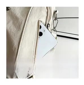 Detail of a beige nylon backpack featuring a functional rear hidden zipper pocket for smartphones