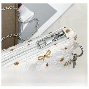 Gros plan sur la trousse de maquillage matelassée avec zip argenté et chaîne de perles