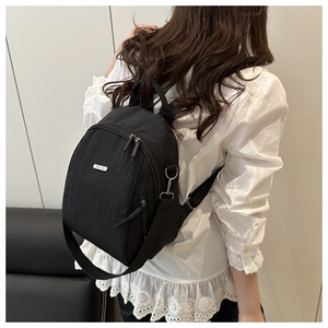 Rear view of a minimalist black nylon backpack on model showing size and fit on back