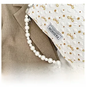 Gros plan sur un sac blanc matelassé avec broderie florale et poignée en perles