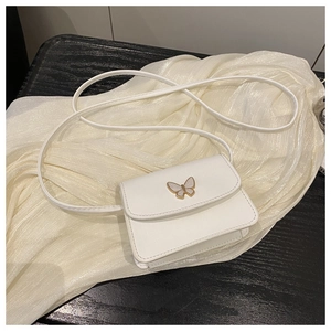 Detail of white mini crossbody bag featuring a golden butterfly hardware clasp design