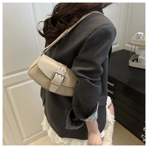 Close-up of minimalist beige saddle bag featuring a stylish large metal buckle detail