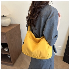 Rear view of model wearing a bright yellow nylon crescent shoulder bag for daily casual use