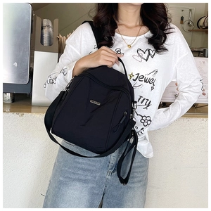 Detail of durable black nylon backpack with silver logo and adjustable canvas straps