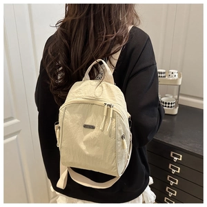 Detail of off-white waterproof nylon backpack showing textured fabric and JING PIN metal logo