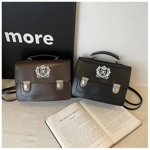 Détail du sac messager vintage montrant le cuir mat et l'écusson blanc imprimé