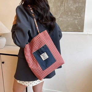 Stylish red checkered canvas tote bag with denim front pocket and woven rope straps