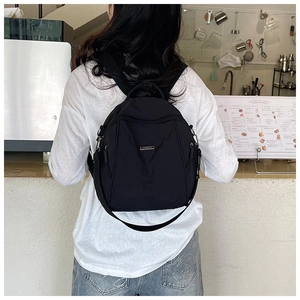 Detail of a black nylon mini backpack featuring multiple zippers and adjustable straps