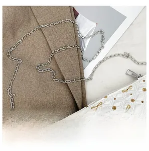 Détail d'un sac matelassé blanc avec motif papillon jaune et bandoulière chaîne argentée
