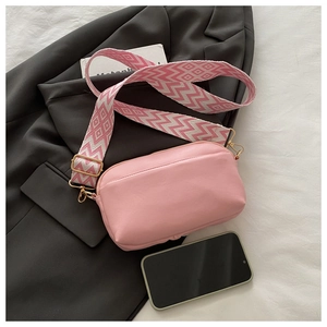 Pink PU leather crossbody bag featuring a wide geometric woven strap and gold zipper