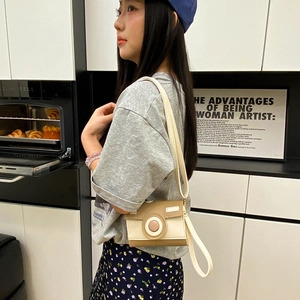 Cute camera shaped crossbody bag in contrast beige and khaki leather worn by a model