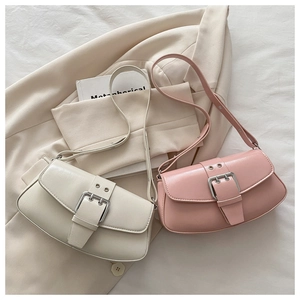 Detail of PU leather shoulder bags in beige and pink with decorative buckle straps