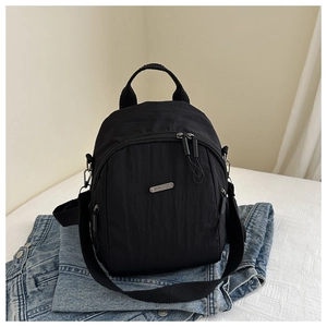 Close-up of black nylon mini backpack featuring a silver metal logo on denim texture