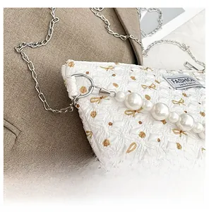 Détail macro du sac en jacquard papillon avec grosses perles et étiquette de mode