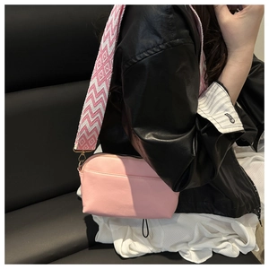 Pink crossbody bag detail with ethnic geometric strap and polished golden hardware