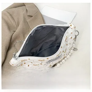 Détails de l'intérieur d'un sac à cosmétiques blanc matelassé avec chaîne de perles