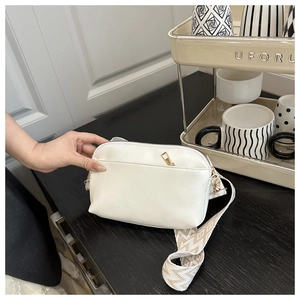 Détail du petit sac bandoulière blanc en cuir avec une large sangle tissée à motifs