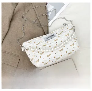 Détail du sac matelassé blanc avec motifs nœuds marron et une grande poignée en perles