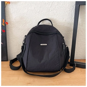 Detail of waterproof black nylon backpack showing metal zippers and brand logo plate