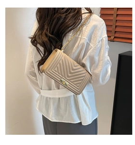 Détail du sac bandoulière beige matelassé en V avec bandoulière chaîne dorée élégante