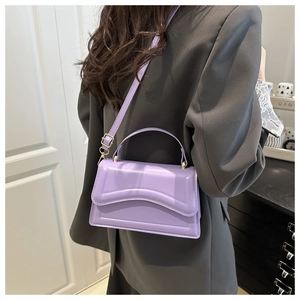 Detail of lavender purple faux leather crossbody bag with wavy stitching on grey blazer