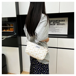 Détail d'un sac à bandoulière matelassé blanc avec anse en perles et nœud papillon doré