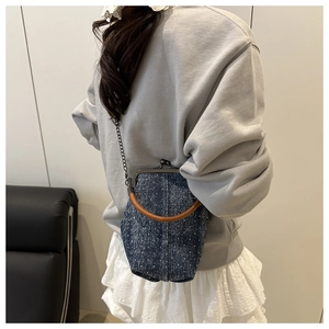 Sac bandoulière en denim à pois avec poignée en bois et chaîne portée par un modèle