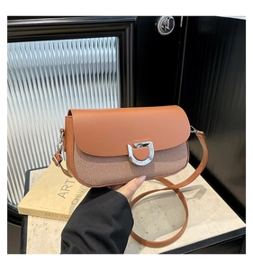 Dettaglio di una borsa a tracolla marrone con patta in pelle e trama tessuta mista