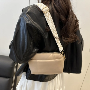 Sac bandoulière carré beige avec large sangle géométrique porté par un mannequin