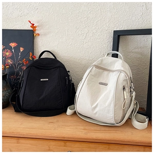 Detailed view of black and beige nylon backpacks displayed on a wooden surface
