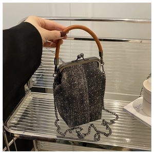 Détail d'un sac à main rétro avec texture gris foncé, poignée en cuir et chaîne