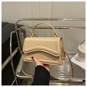 Detail of cream leather handbag with wavy embossed flap and light gold hardware