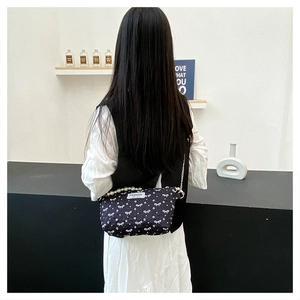 Détail du sac de maquillage matelassé noir avec imprimés papillons et chaîne de perles