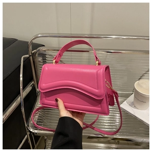 Detail of hot pink leather bag featuring wavy embossed patterns and pale gold hardware