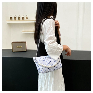 Détail du sac matelassé avec nœuds bleus, poignée en perles et bandoulière en métal