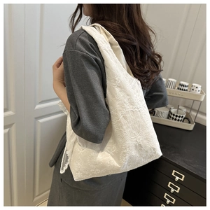 Detail of elegant white lace floral canvas tote bag featuring intricate crochet patterns