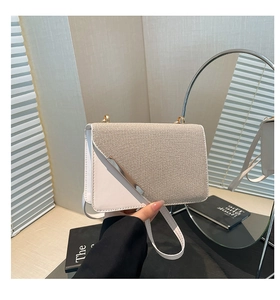 Detail of crossbody bag with beige woven texture, white leather, and silver metal bar