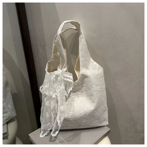 Detail of white lace tote bag with floral embroidery and large bow accent