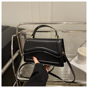 Detailed view of black quilted leather handbag with wavy stitching and gold hardware