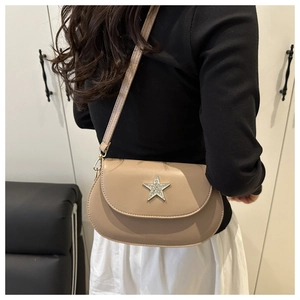 Detail of a beige leather crossbody bag featuring a large sparkling rhinestone star accent