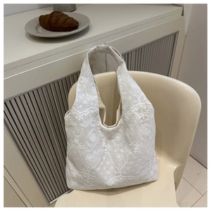 Detailed view of beige lace flower embroidery on a soft canvas tote bag texture