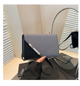 Close-up of contrast color crossbody bag with textured fabric and metallic edge detail
